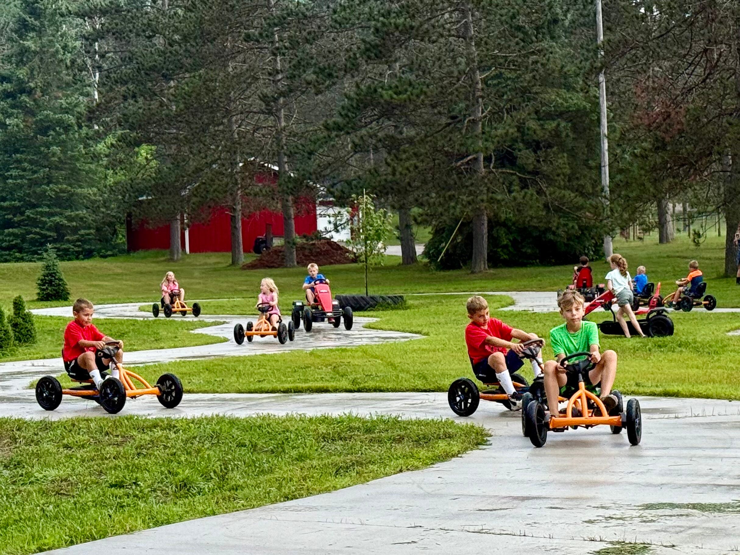 Children racing red pedal karts on the paved track at Wilderness Valley Farm in Gaylord, Michigan